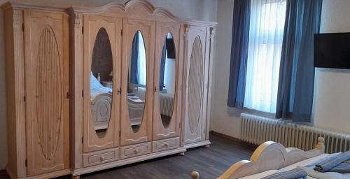 a bedroom with a large wooden cabinet with mirrors at Landgasthof Hotel Zur Waage in Marienhafe