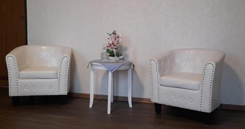 twee witte stoelen en een tafel met bloemen erop bij Landgasthof Hotel Zur Waage in Marienhafe