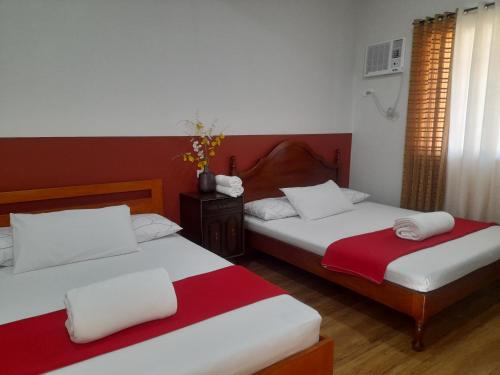 two beds in a room with red and white at Doroteo's Transient House in Calingcuan