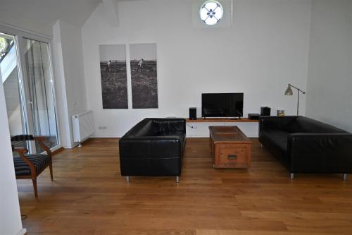 a living room with two black couches and a tv at Schrotboden in Geschendorf