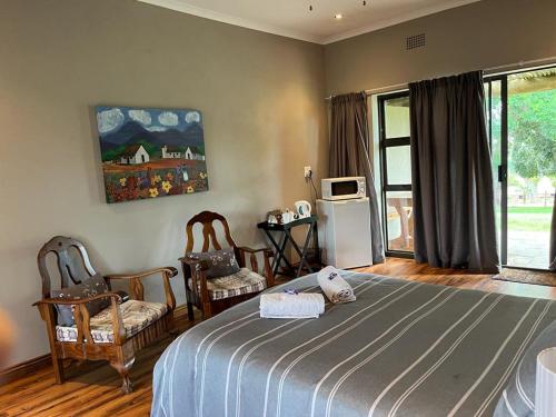 a bedroom with a bed and chairs and a window at Berlouri Guest House in Hekpoort