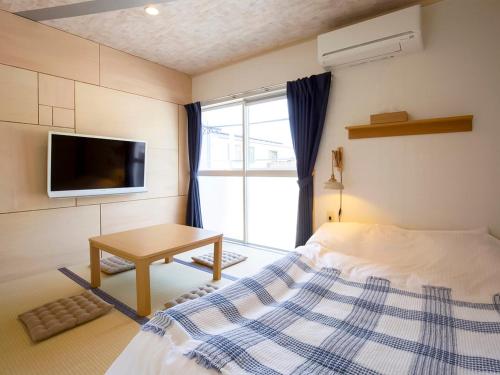 a bedroom with a bed and a tv and a table at Guesthouse Life Field in Kurashiki
