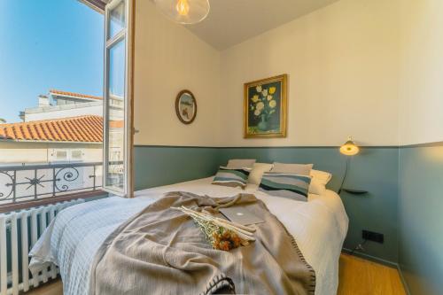 a bedroom with a bed and a large window at Papagayo, appartement halles et côte des basques in Biarritz