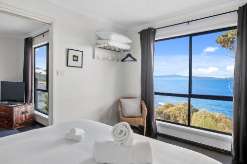 a bedroom with a large window with a view of the ocean at Hamptons on the Bay in Swansea