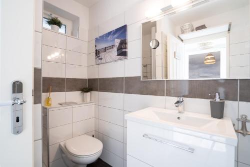 ein weißes Bad mit einem WC und einem Waschbecken in der Unterkunft Haus Sielbeck, Traumblick in Sielbeck