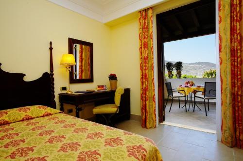 a hotel room with a bed and a desk and a balcony at Arciduca Grand Hotel in Lipari