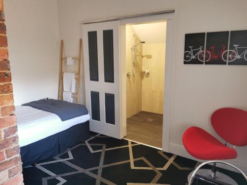 a bedroom with a bed and a shower and a red chair at The Empire Hotel Deloraine in Deloraine