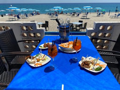 Partenone Resort Hotel في رياس مارينا: طاولة زرقاء مع أطباق من الطعام على الشاطئ