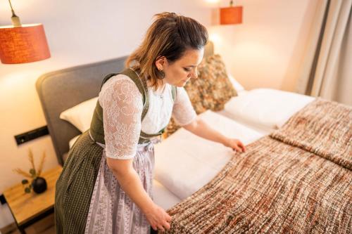 a woman is standing next to a bed at Apartment Schichlreit in Annaberg im Lammertal