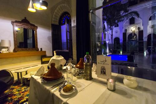 a table with a white table cloth and a window at Riad Braya in Fès