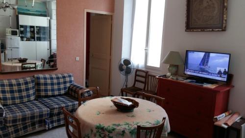 uma sala de estar com uma mesa e uma televisão em 35 ter rue du Docteur Marçon em Bandol