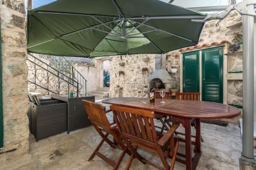 a wooden table and chairs with a green umbrella at ToMaDi Residence in Split