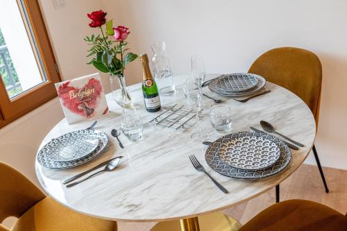 een witte tafel met borden en een fles wijn bij L'elegant - Appart'Hotel Le Gatsby in Saint-Quentin