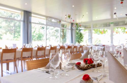 艾因西德倫的住宿－Hotel Allegro Einsiedeln，用餐室配有带玻璃杯和玫瑰的桌子