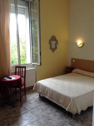 a bedroom with a bed and a table and two windows at Hotel Acapulco in Montpellier
