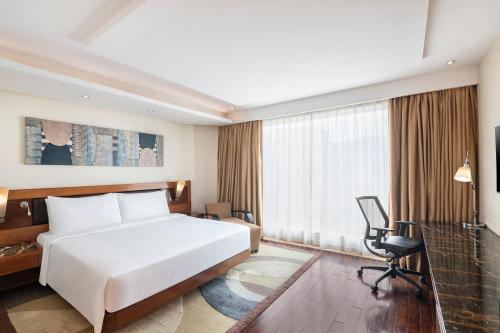 a bedroom with a white bed and a desk and a chair at Radisson Blu Kaushambi Delhi NCR in Ghaziabad