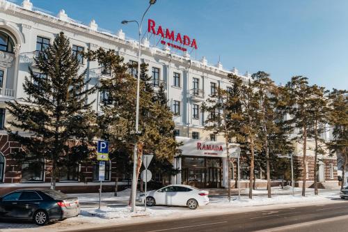 a building on a street with cars parked in front at Ramada by Wyndham Astana in Astana