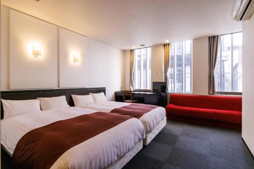 a hotel room with a large bed and a red couch at Hotel Fosse Himeji in Himeji