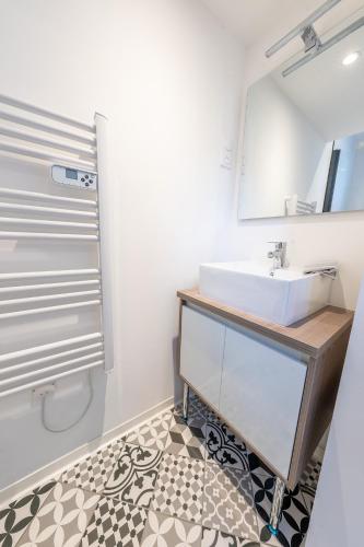 une salle de bain avec un lavabo et un miroir dans l'établissement Le Nid - Appart'Hotel Le Gatsby, à Saint-Quentin