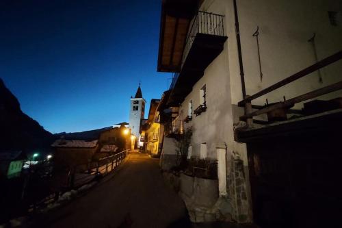 a dark street with a building and a clock tower at night at Lo solan in Valpelline