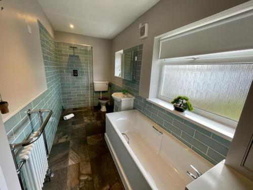 baño con bañera, aseo y ventana en Cherry Tree Lodge, en Norwich