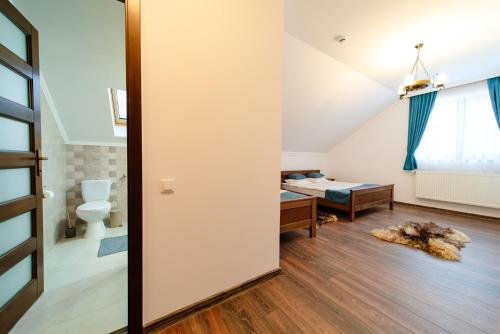 baño con aseo y cama en Transylvanian Relax House, en Lupeni