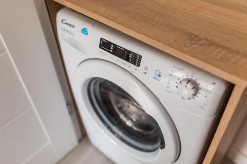 a washing machine in a kitchen with a wooden counter at Simply Modern Apartments in Toruń
