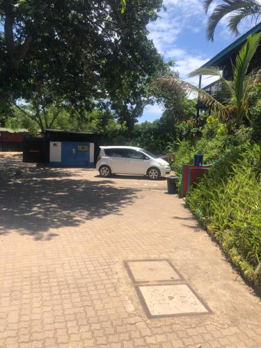 a white car parked in a parking lot at Tri M Waves Lodge in Ponta do Ouro