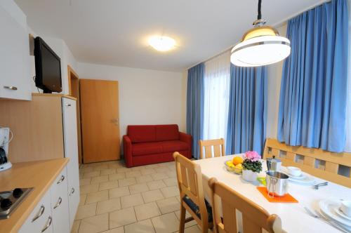 eine Küche und ein Esszimmer mit einem Tisch und einem roten Stuhl in der Unterkunft Appartments Marlena in Niederdorf