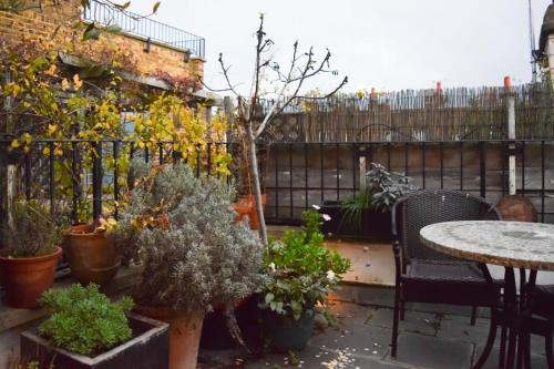um pátio com mesas e vasos de plantas e uma cerca em Stylish and Spacious Apartment with Terrace em Londres