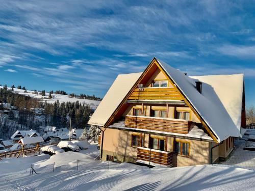 a wooden house in the snow with snow at Willa "NA KLINKU" in Dzianisz