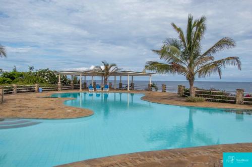 a swimming pool with a gazebo and the ocean at Palm Grey Villa By YourHost Vipingo Beach Kilifi in Kijipwa