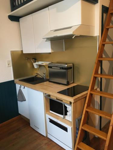 une cuisine avec des placards blancs, un four micro-ondes et une échelle dans l'établissement Petit studio, plein centre ville, grande terrasse, à Bagnères-de-Bigorre