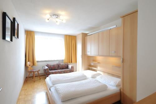ein Schlafzimmer mit einem Bett und einem Stuhl in einem Zimmer in der Unterkunft Appartments Marlena in Niederdorf