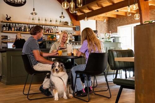 a group of people sitting at a table with a dog at TopParken - Resort Veluwe in Garderen