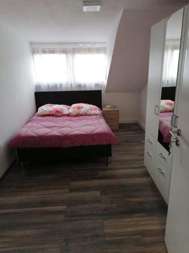 Ferienwohnung Andreea في سارلويس: غرفة نوم مع سرير مع لحاف وردي