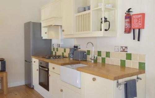 a kitchen with white cabinets and green and white tiles at Wild Coastal Retreat at Troed Y Rhiw Aberporth in Aberporth