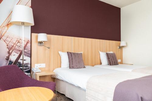 a hotel room with two beds and a chair at Mercure Gdynia Centrum in Gdynia