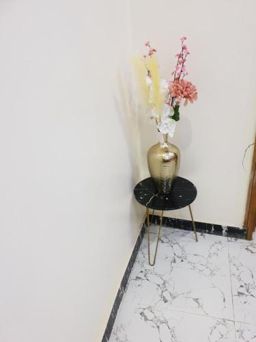 a vase with flowers on a table next to a wall at NESTAPARTMENTS , Orchid Road , VAN DANIEL'S STREET, LEKKI , Ensuite ,WiFi in Lagos
