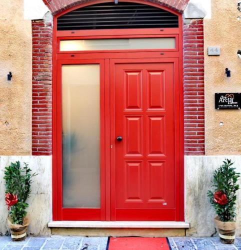 een rode deur op een bakstenen gebouw met twee planten bij TRE ARCHI HOUSE in Chiusi