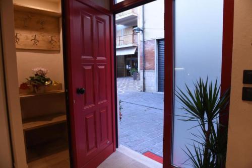 een rode deur die leidt naar een hal met een plant bij TRE ARCHI HOUSE in Chiusi