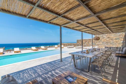a dining room with a table and a swimming pool at Blue Gres Villa Tinos in Tinos