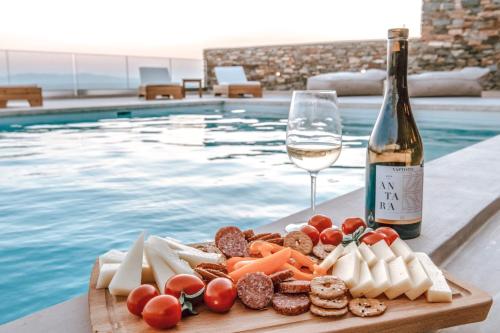 a plate of food and a glass of wine next to a swimming pool at Blue Gres Villa Tinos in Tinos Town