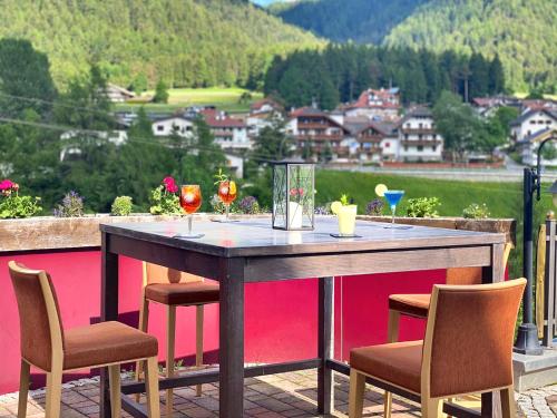 a table with two chairs and wine glasses on a balcony at Smy Koflerhof Wellness & Spa Dolomiti in Rasun di Sopra