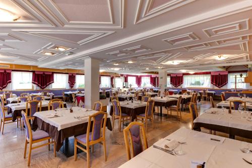 a dining room with tables and chairs and red curtains at Smy Koflerhof Wellness & Spa Dolomiti in Rasun di Sopra
