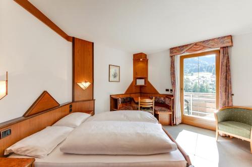 Schlafzimmer mit einem Bett, einem Schreibtisch und einem Fenster in der Unterkunft Smy Koflerhof Wellness & Spa Dolomiti in Oberrasen