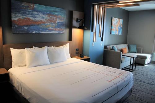 a hotel room with a large bed and a living room at La Quinta Inn & Suites by Wyndham Bardstown in Bardstown