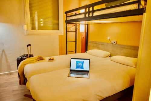 a laptop computer sitting on top of a bed at ibis Budget Colmar Centre Gare in Colmar