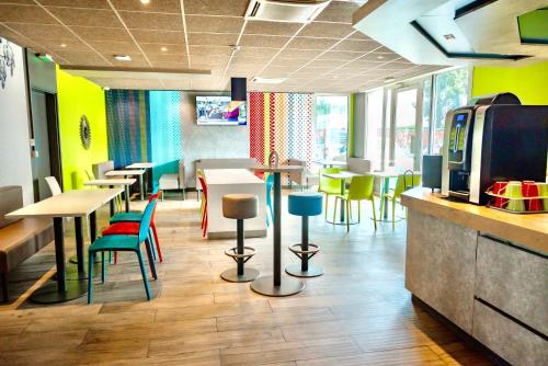 un restaurant avec des tables et des chaises colorées et un bar dans l'établissement ibis Budget Colmar Centre Gare, à Colmar