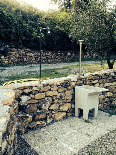 a stone wall with a bench and a street light at Casa vacanze gli ulivi in Borgomaro